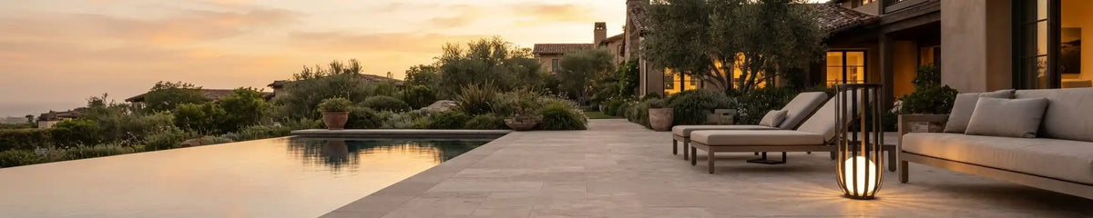 Modern decorative floor lamp with a warm glow placed on a patio near a pool, illuminating outdoor lounge seating at dusk.
