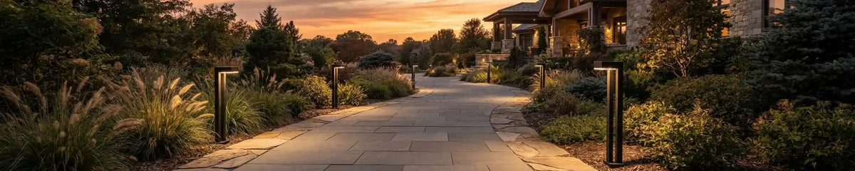 Curved stone driveway lined with sleek rectangular pathway lights, illuminating the landscaping and leading to a luxury home entrance at dusk