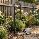 Solar-powered garden light in a garden setting with flowers and a wooden fence.