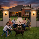 Family with children and a dog sitting around a table in a backyard at dusk.