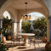 Farmhouse style wicker pendant lamp over wooden dining table on covered porch with garden view