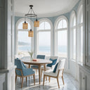 Modern rattan cluster light hanging in bright bay window dining area with ocean view