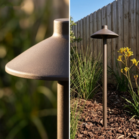 Garden light fixture in outdoor setting with plants and wooden fence.