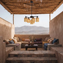 Close up of black five-arm chandelier featuring handwoven rattan cylinder drum shades