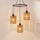 Close up of black metal three-light chandelier with handwoven rattan cylinder shades
