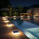 Pool area with solar lights on a wooden deck at night