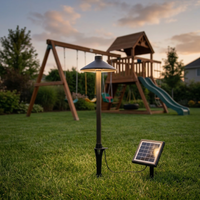 Solar-powered outdoor lamp in a backyard with playground equipment.