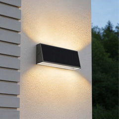 Tenox PT0716 solar wall light casting warm up and down beams on a modern exterior wall