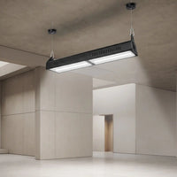 A modern rectangular industrial ceiling light fixture with a black housing and bright white illuminated panels, suspended from the ceiling in a minimalist concrete and plaster interior space.