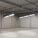 Two long rectangular industrial LED underfloor lights suspended from the ceiling of a large concrete warehouse or studio space.