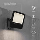 Black OUTLUX 150W outdoor floodlight mounted on a gray concrete wall, with rain-like streaks and text highlighting weather-resistant and impact-resistant features, plus icons for sunny, snowy, foggy, and rainy conditions.