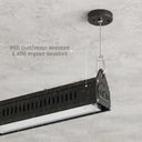 A black industrial ceiling-mounted light fixture shown hanging from a ceiling in a rain-swept environment, with overlaid text reading 'IP65 Dust/Water Resistant & IK06 Impact-Resistant.' This is not a clean product-only studio shot because the real environment and rain create a lifestyle-like presentation, so subject_type is Lifestyle rather than Product/Packaging or Instruction Diagram.