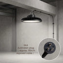 A black industrial-style pendant light hanging from a ceiling in a concrete warehouse or studio space. The light has a ribbed shade and an adjustable arm extending to the right.