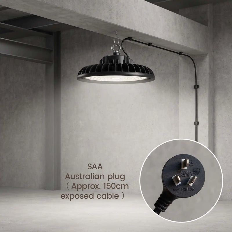 A black industrial-style pendant light hanging from a ceiling in a concrete warehouse or studio space. The light has a ribbed shade and an adjustable arm extending to the right.