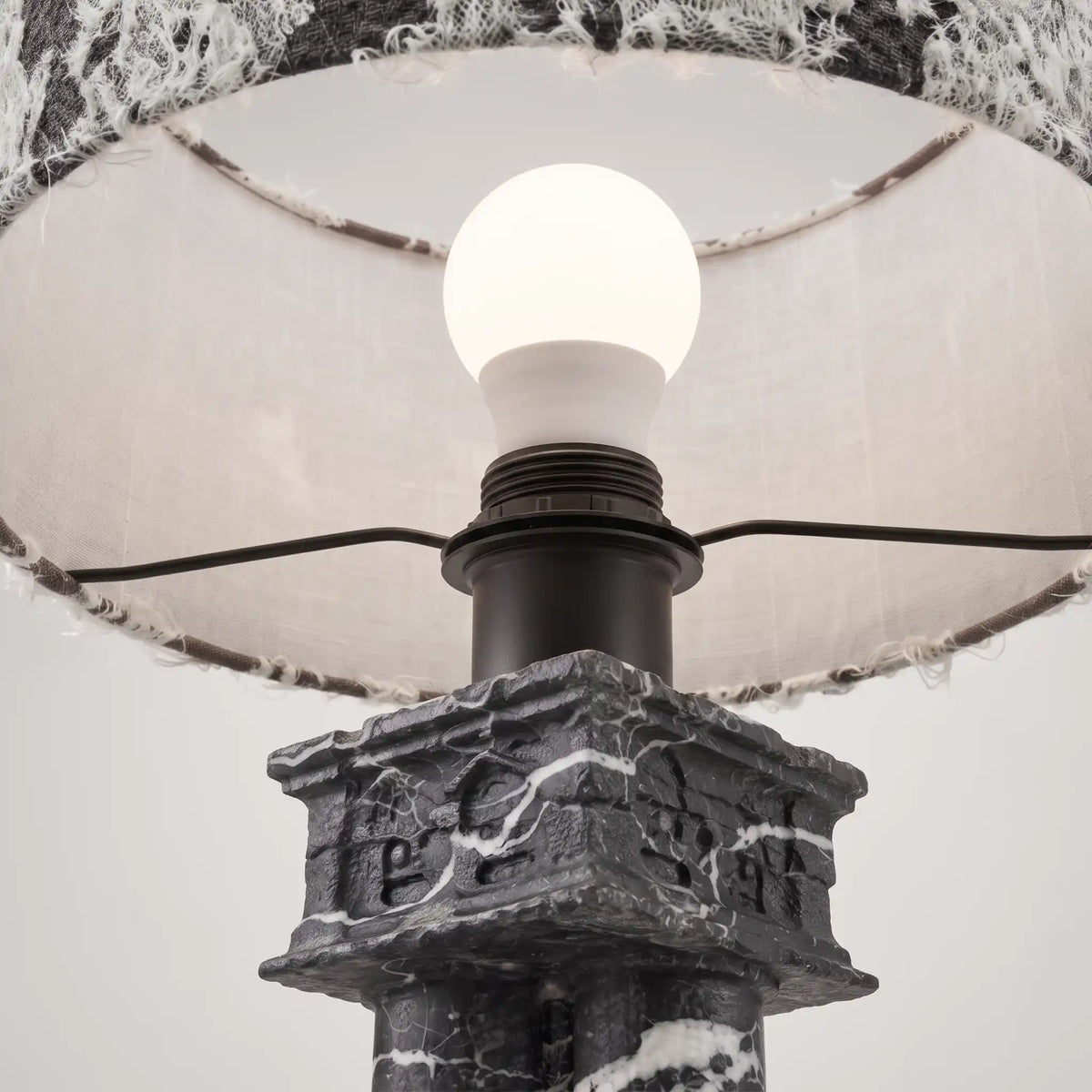 Close-up of the E27 bulb and lamp holder above the carved Black Vein Marble base of Silent Rift