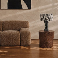 Silent Rift Black Vein Marble table lamp on a round wood side table beside a brown lounge chair